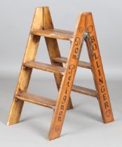 A modern wooden folding stepladder, signwritten to the sides with champagne advertising, height