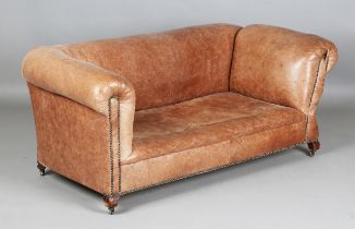 An early 20th century two-seat drop-end Chesterfield settee, upholstered in brown leather, on square