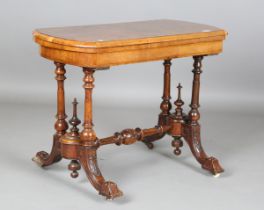 A late Victorian walnut and boxwood inlaid fold-over card table, raised on turned supports and