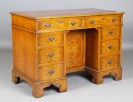 A late 20th century walnut twin pedestal desk, fitted with an arrangement of oak-lined drawers,