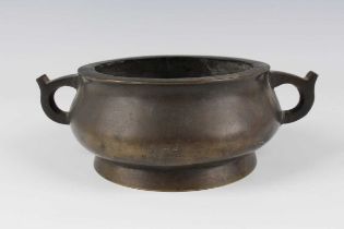 A Chinese brown patinated bronze bombé censer, Qing dynasty, the low-bellied circular body flanked