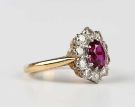 A gold, ruby and diamond oval cluster ring, claw set with the oval cut ruby within a surround of ten