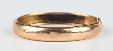 A gold oval hinged bangle, unmarked, weight 12.9g, inside width 5.7cm.