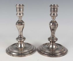 A pair of Elizabeth II silver Queen Ann style cast candlesticks, each with cylindrical sconce