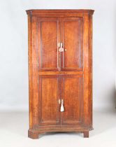 A George III provincial oak floor-standing corner cabinet, fitted with four panelled doors, height