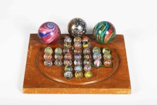 An early 20th century twin-sided solitaire games board with thirty-three spiral decorated marbles,