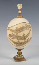 An early 20th century Australian ostrich egg, decorated with a trailing panel of lizards and mounted