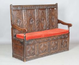 An early 18th century provincial oak panelled settle, the carved back above a box seat, height 99cm,