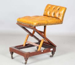 A Victorian mahogany adjustable footstool, upholstered in buttoned tan leather, the double ratchet