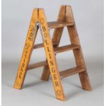 A modern stepladder, signwritten to the sides with champagne advertising, height 81cm, depth 43cm.