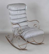 A late 19th/early 20th century wrought iron framed rocking armchair, upholstered in patterned blue