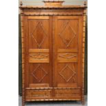 A late 19th century French pitch pine and faux bamboo wardrobe, the two doors enclosing later fitted