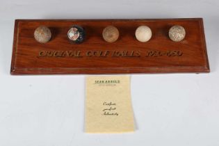 A group of five early/mid-20th century golf balls, mounted on an inscribed display stand, width