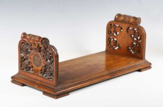 A mid-Victorian walnut bookstand, each finely carved end panel inlaid with initials, the platform