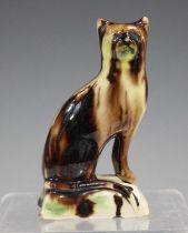 A Whieldon type glazed pottery model of a cat, circa 1800, modelled seated on a rectangular base,