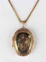 A gold oval pendant locket with scroll engraved decoration, unmarked, weight 5.1g, length 3.9cm,