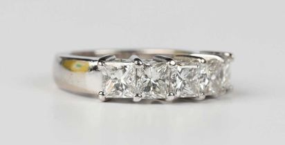 A diamond five stone ring, claw set with a row of princess cut diamonds, unmarked, weight 8.3g,