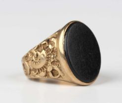 A 9ct gold and black onyx oval signet ring, with cast scrolling decoration to the shoulders,