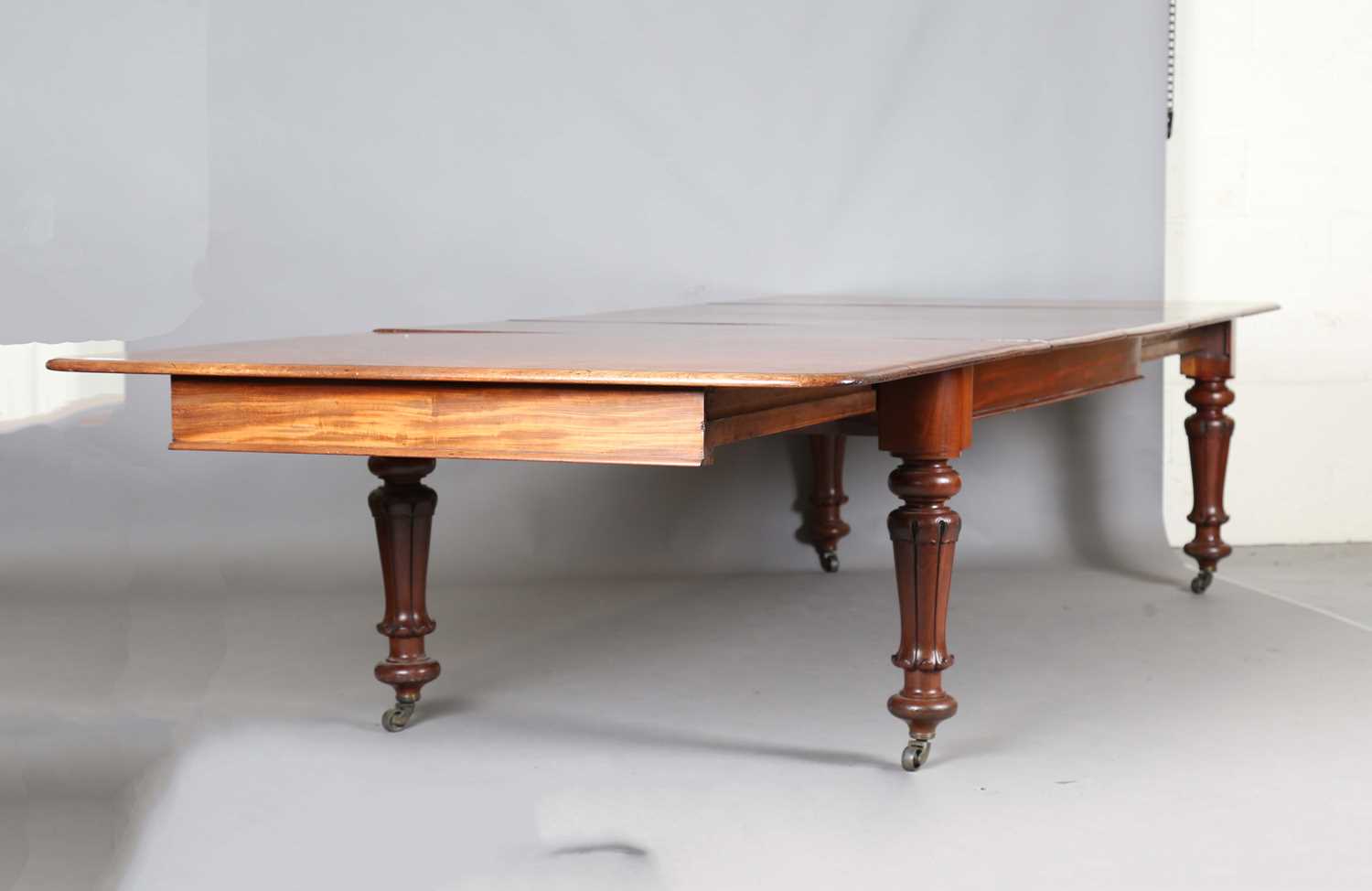 A large early Victorian mahogany pull-out extending dining table, the rectangular top with three