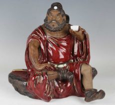 A Chinese Shiwan pottery sang-de-boeuf glazed figure of an immortal, mid-20th century, modelled