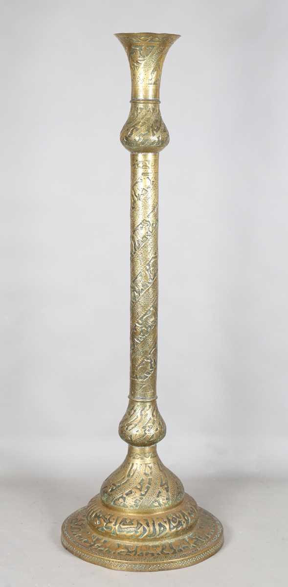 An Islamic brass floor lamp, circa 1900, the flared surmount and cylindrical column decorated with