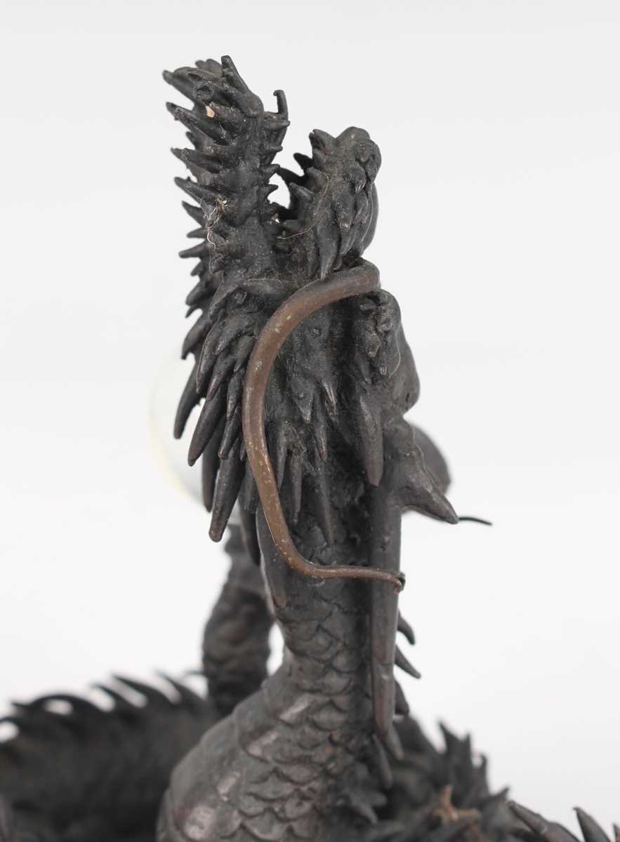 A Japanese cast bronze figure of a dragon, 20th century, modelled in a coiled pose holding a - Image 2 of 9