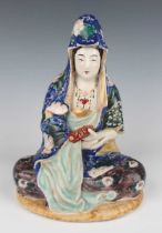 A Japanese Kutani porcelain figure of Kannon, Meiji period, modelled seated wearing a colourful robe