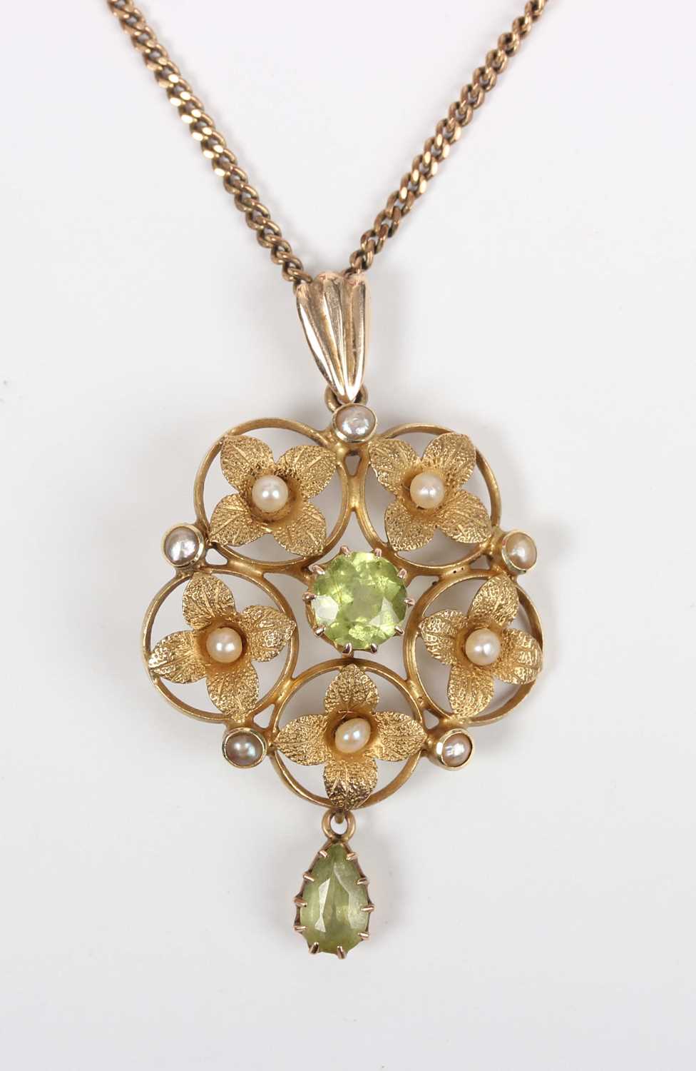 An Edwardian gold, peridot and seed pearl pendant in a cinquefoil shaped design, claw set with the