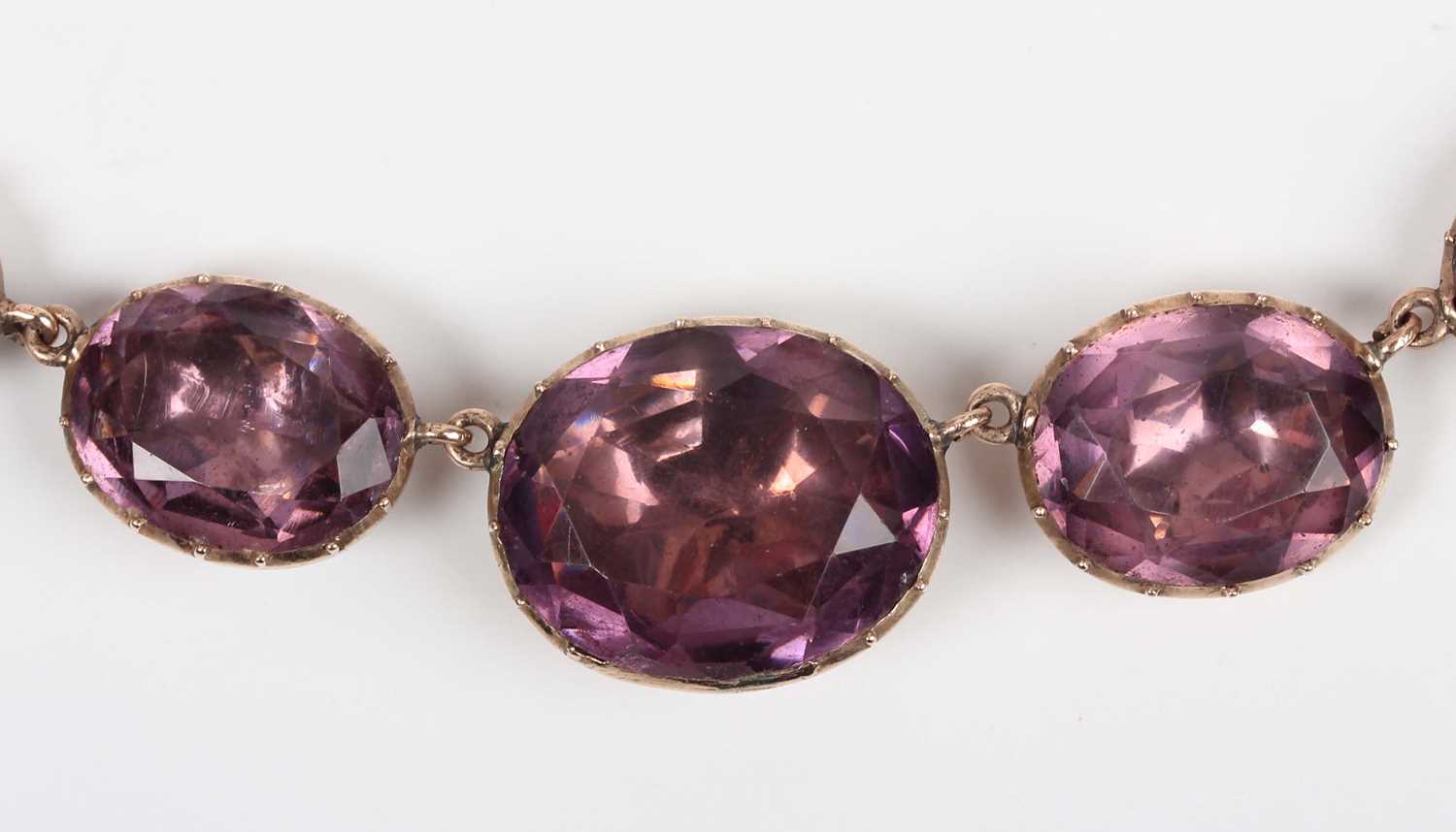 A Georgian gold and foil-backed mauve paste necklace, mounted with a row of graduated oval cut mauve - Image 2 of 4