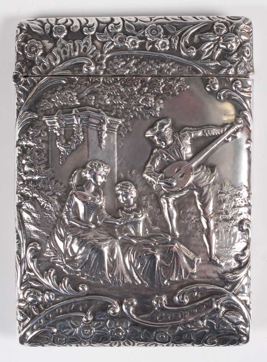 An Edwardian silver rectangular card case, the front decorated in relief with a musician and two