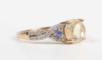 A 14ct gold ring, mounted with a central cabochon pale yellow opal between diamond and pale blue gem