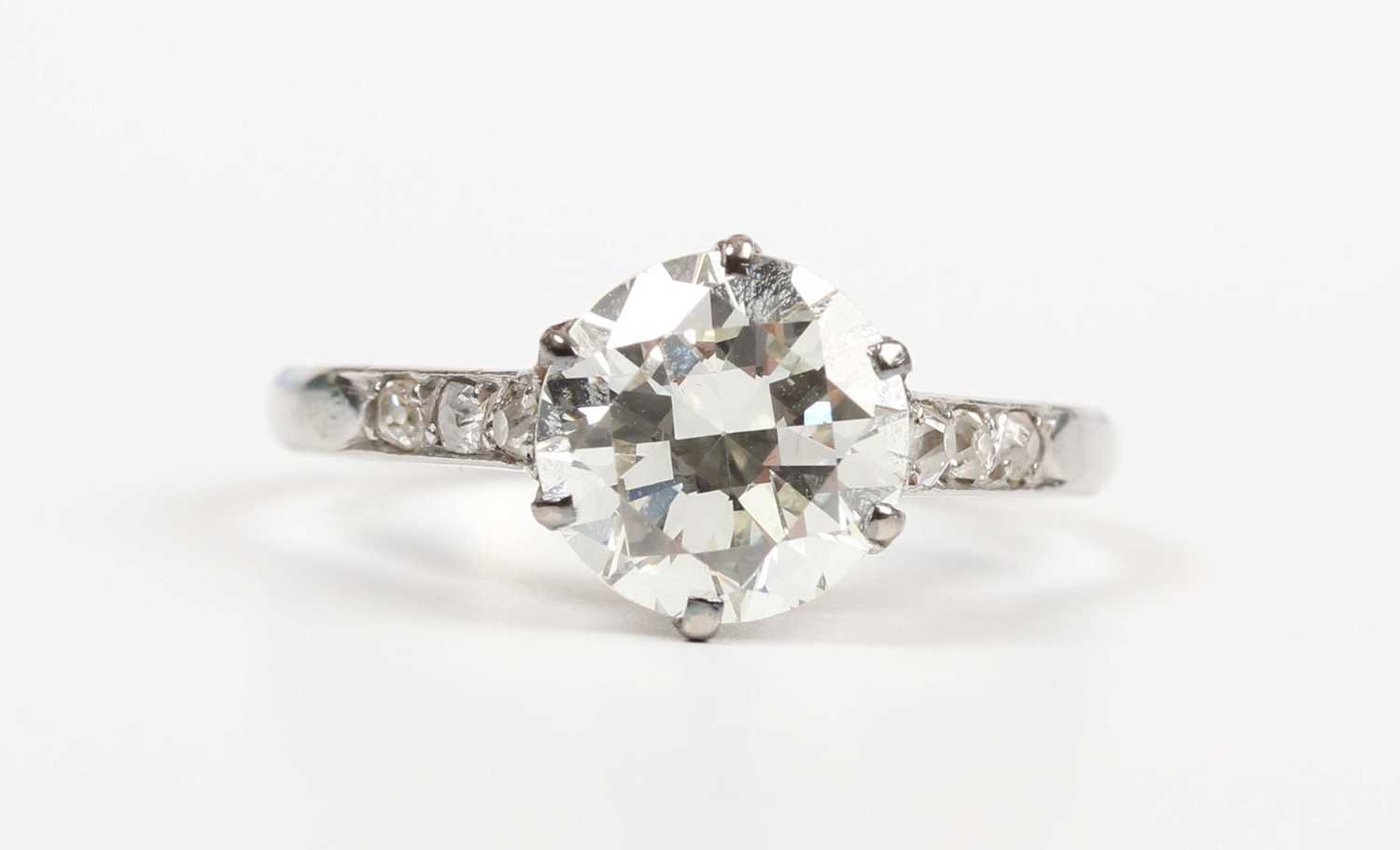 A platinum and diamond ring, claw set with the principal circular cut diamond between diamond - Image 2 of 5