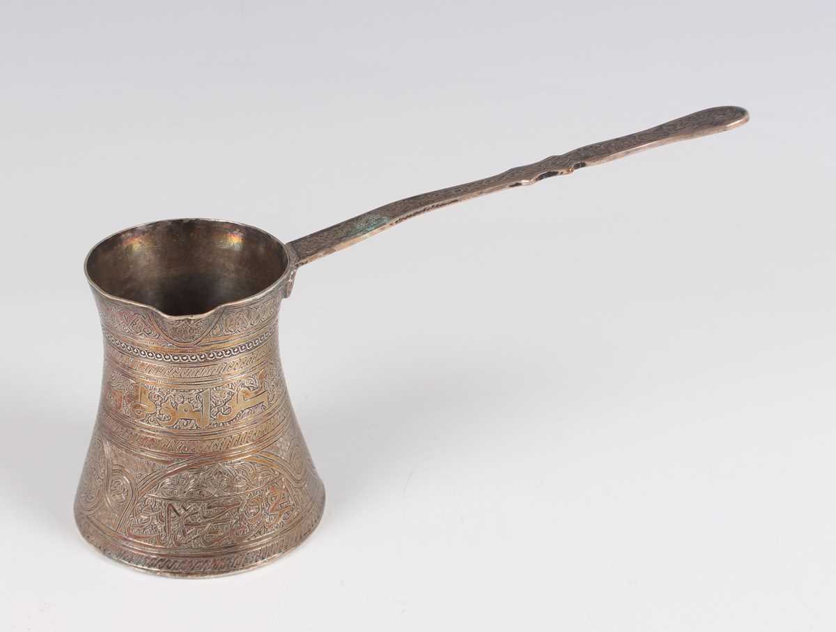 An Egyptian silver coffee pot of waisted cylindrical form with pouring lip and flat handle, all