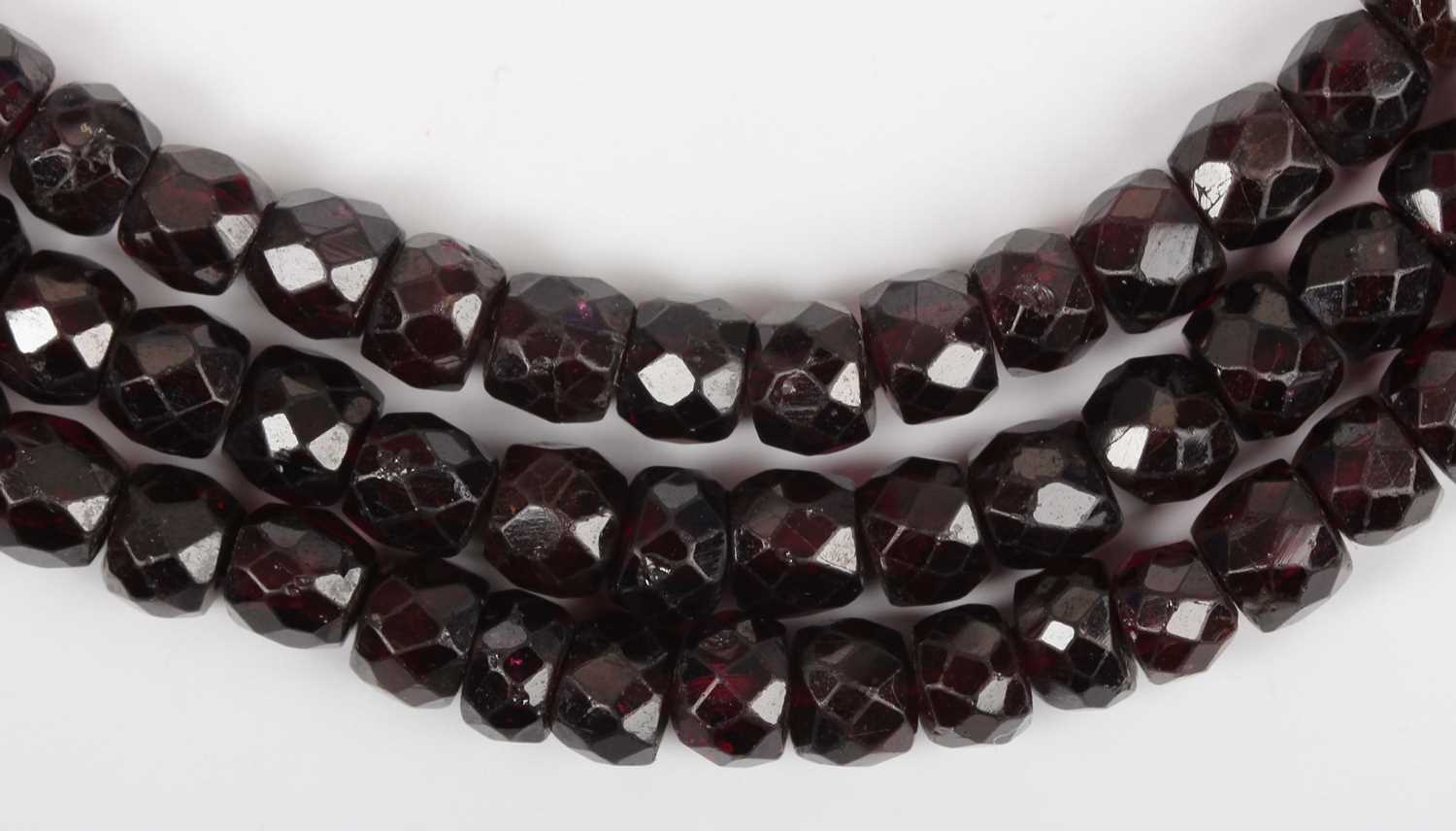 A three row necklace of faceted garnet and red paste beads, on a gold and faceted garnet oval clasp, - Image 3 of 4