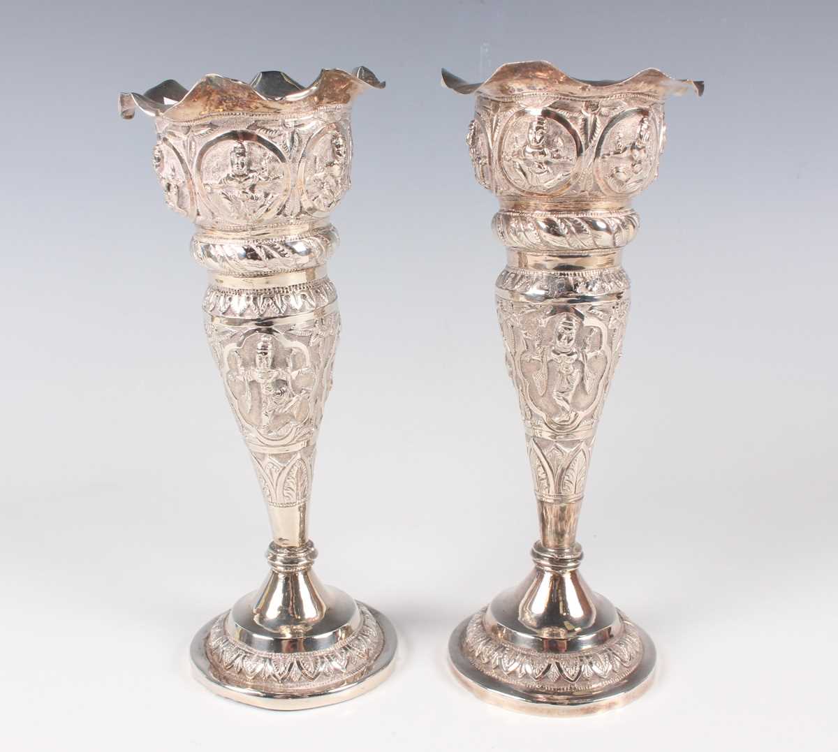 A pair of Burmese silver spill vases, each with frilled rim above embossed deities and foliate - Image 2 of 3