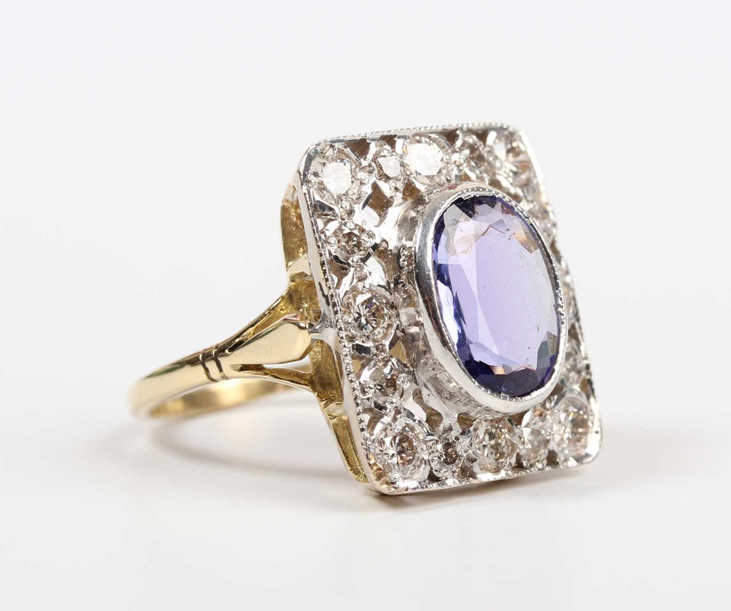 A gold, tanzanite and diamond panel shaped ring, collet set with the oval cut tanzanite within a