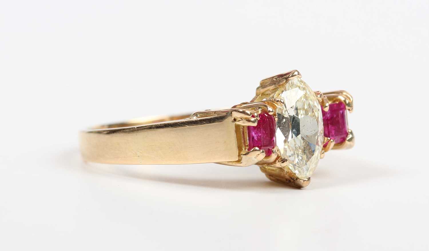 A gold, diamond and ruby ring, claw set with the marquise shaped diamond between two square cut