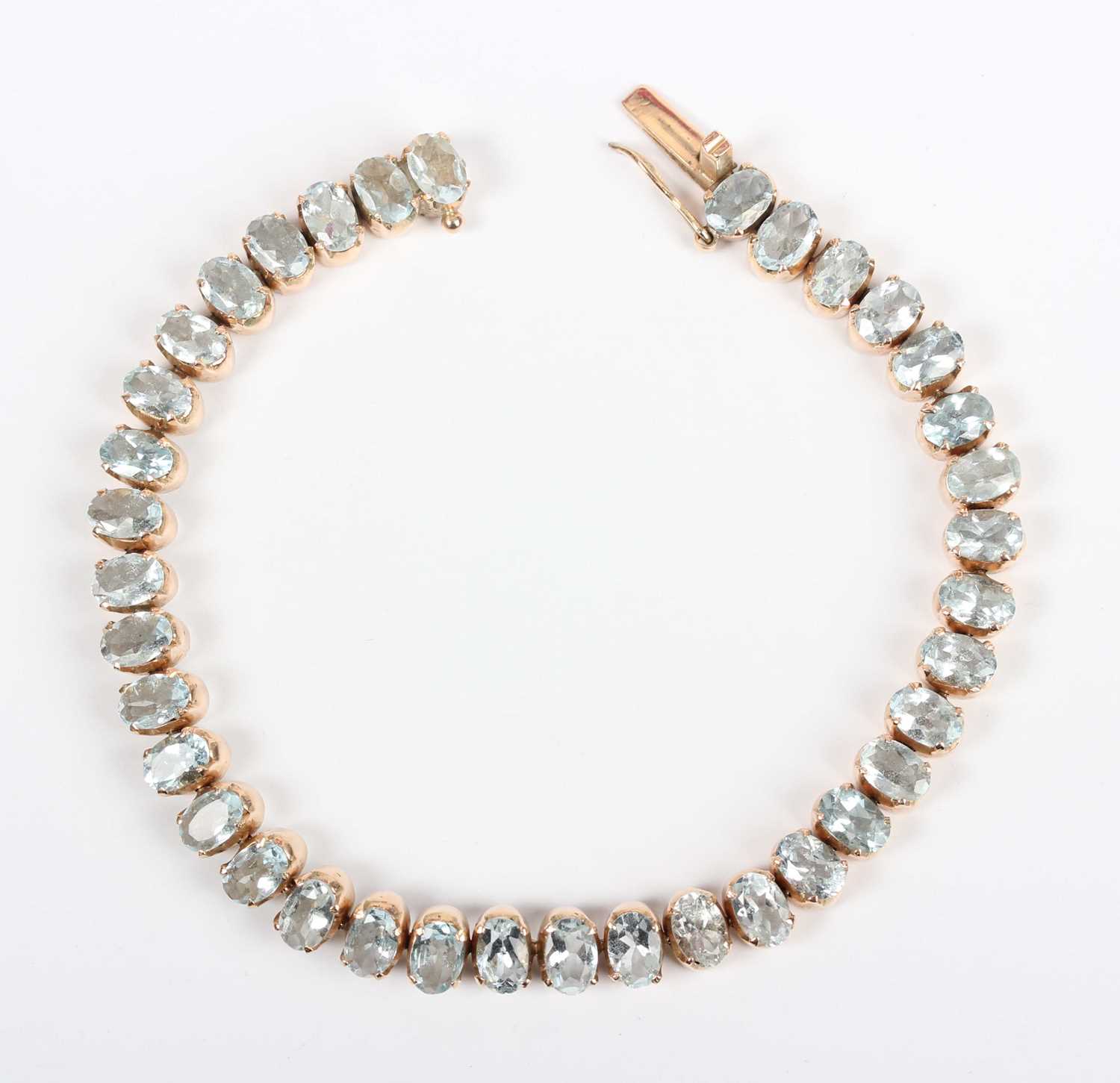 A gold and aquamarine bracelet, claw set with a row of oval cut aquamarines, on a snap clasp,