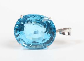 A white gold pendant, claw set with a large oval mixed cut treated blue topaz, detailed ‘18K’,