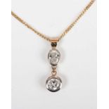 A gold and diamond two stone pendant, collet set with a circular cut diamond below an oval cut