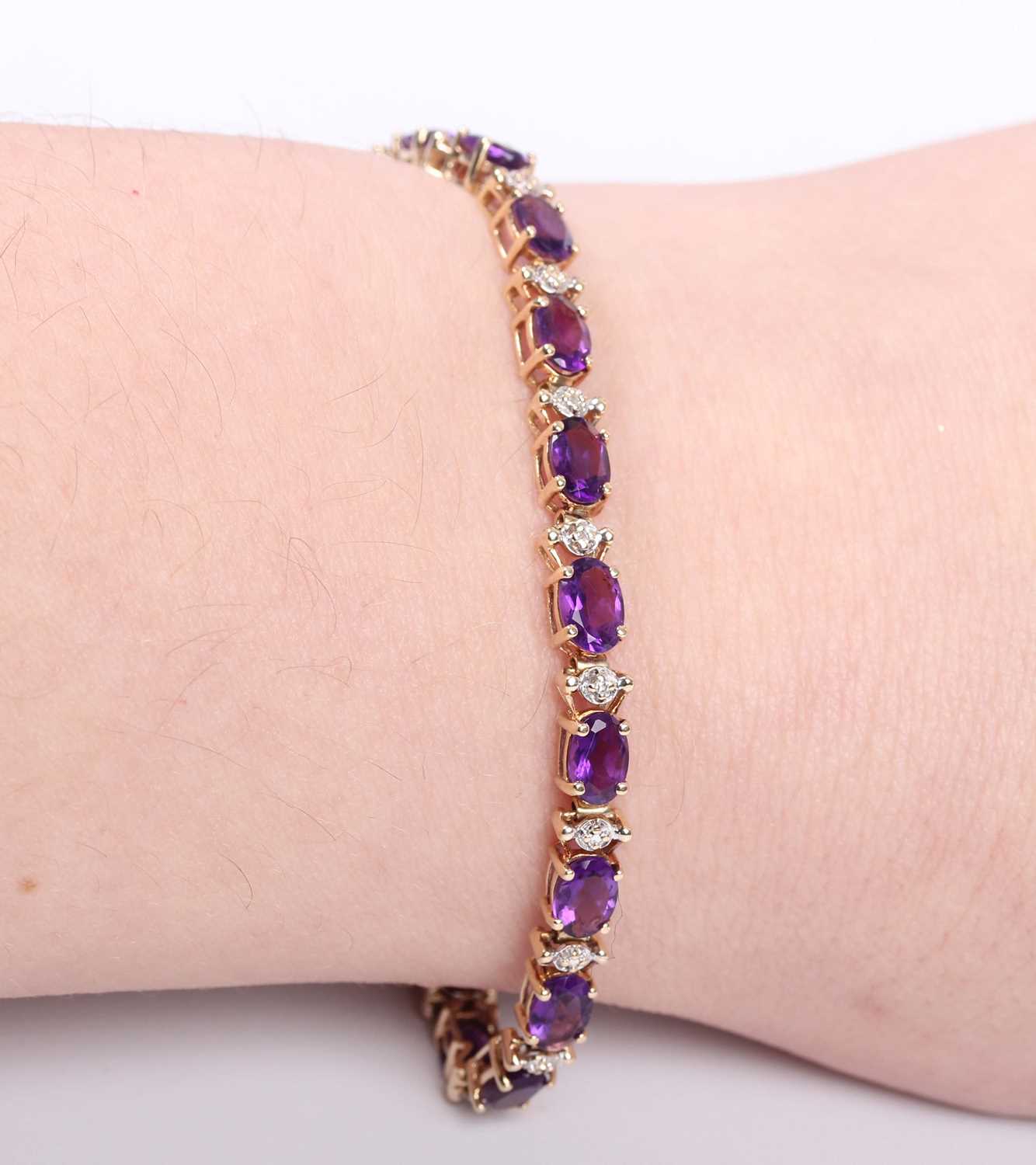 A gold and amethyst bracelet, claw set with a row of oval cut amethysts, detailed ‘10K’, on a sprung - Image 3 of 3