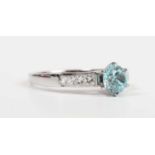 An 18ct white gold, blue zircon and diamond ring, claw set with the circular cut blue zircon between