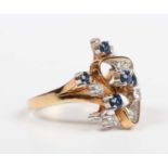 A gold, sapphire and diamond ring in an abstract design, claw set with five circular cut