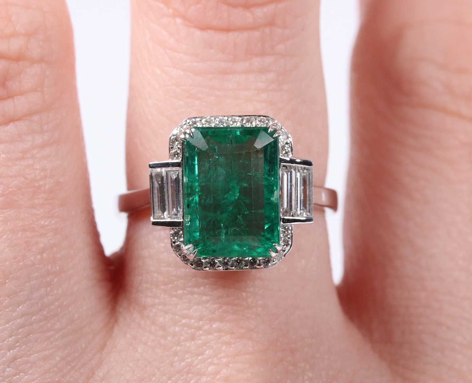 A white gold, treated emerald and diamond ring, claw set with a cut cornered rectangular step cut - Image 5 of 6