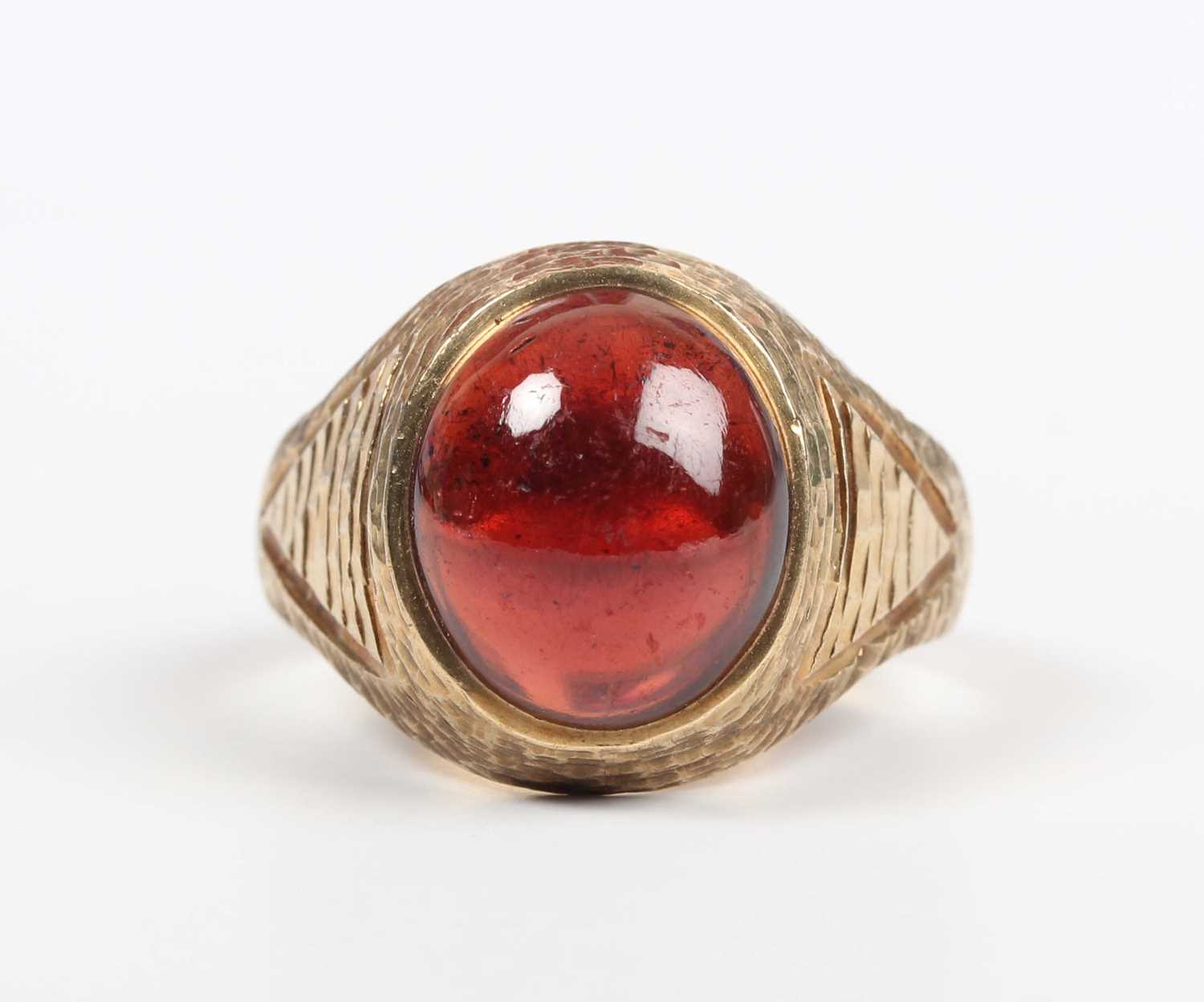 A 9ct gold and carbuncle garnet ring, mounted with an oval carbuncle garnet between textured - Image 2 of 5