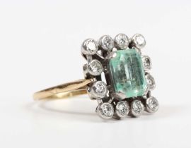 A gold and platinum, emerald and diamond cluster ring, claw set with the cut cornered rectangular