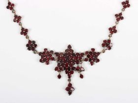 A Bohemian garnet necklace, the front designed as a six pointed starburst shaped cluster, the