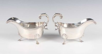 A pair of George III silver sauceboats, each with gadrooned rim and foliate capped scroll handle, on
