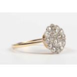 A gold, platinum and diamond cluster ring in a shaped circular design, mounted with old cut