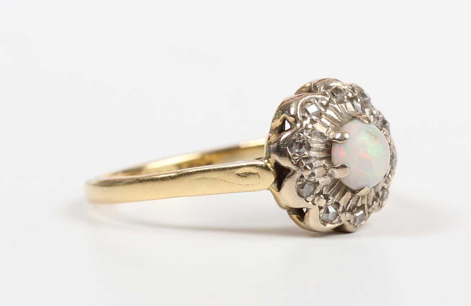 A gold, opal and diamond cluster ring, claw set with the circular opal within a diamond set